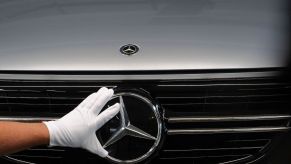 An employee adjusts a Mercedes-Benz three-pointed star emblem at an assembly line for GLC sports utility vehicle