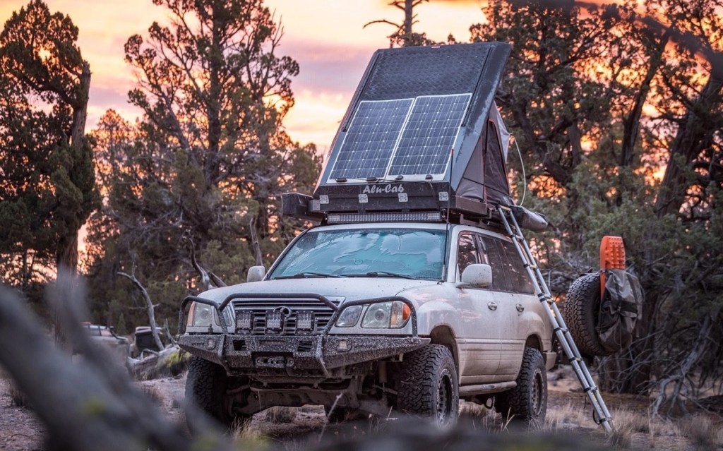 A modified 2005 Lexus LX470 in the wilderness with its rooftop tent open