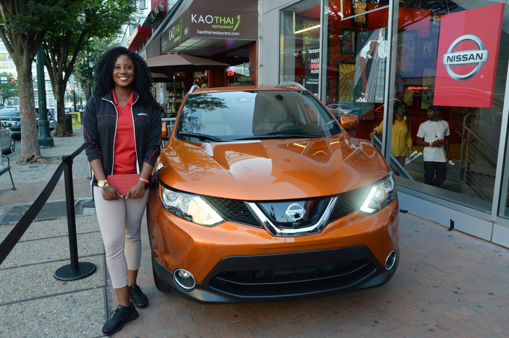 A woman standing next to a Nissan Rogue