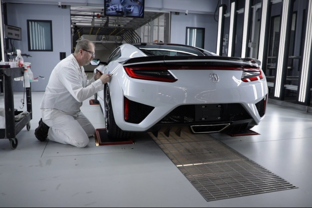A paint tech inspects the paint of a white acura nsx
