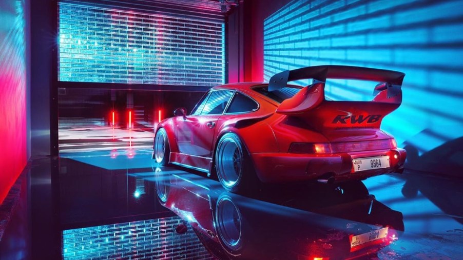 Rear view of a red RWB Porsche 911 as it sits in a neon-blue-lit garage