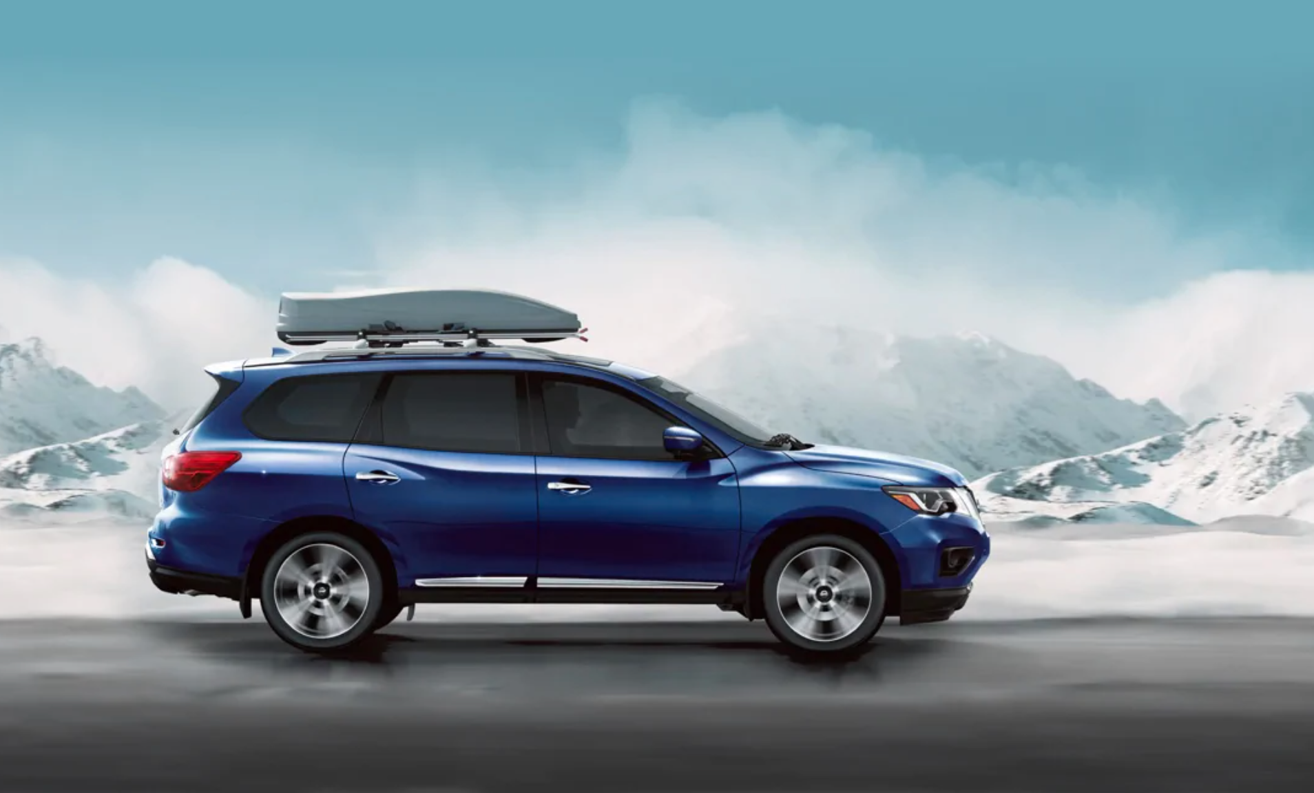 A blue 2020 Nissan Pathfinder driving down snowy road