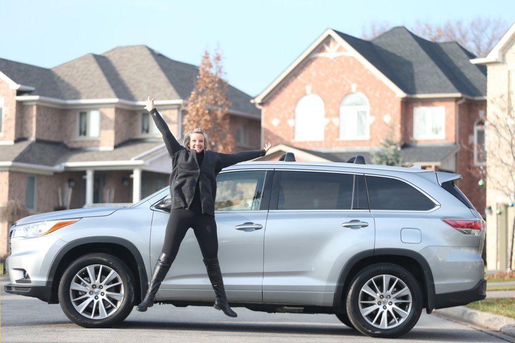 A woman posing in front of her Toyota Highlander