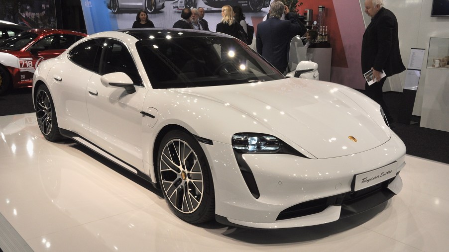 A white Porsche Taycan turbo on display at an auto show