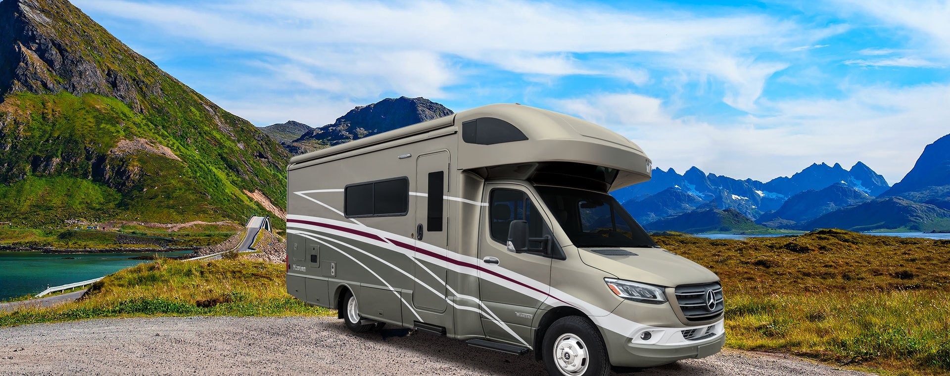 A Winnebago Navion RV sits in a valley on a nice blue-sky day.