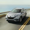 a silver top trim HR-V driving fast on a scene road by the shore