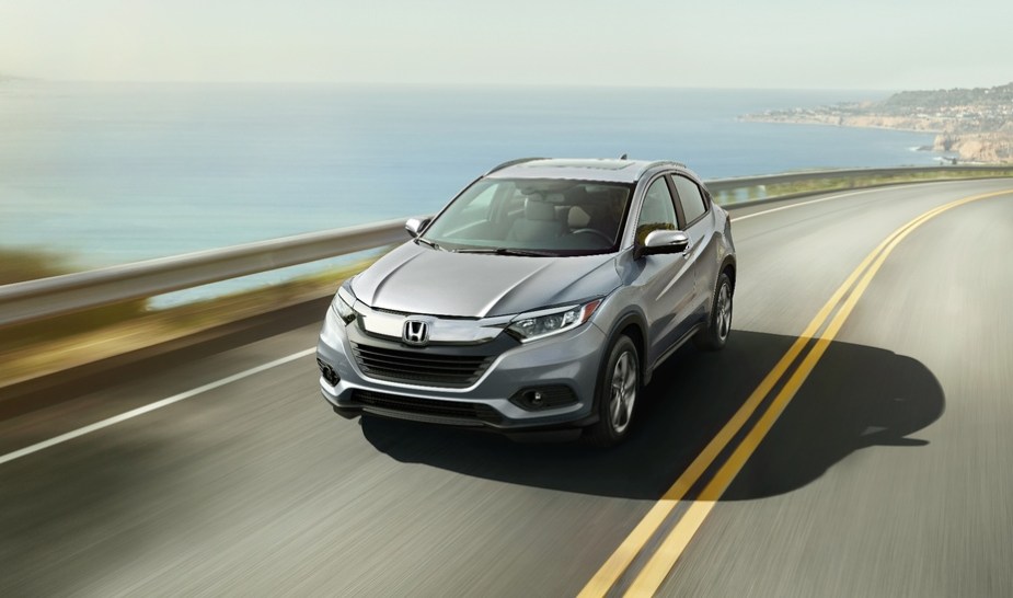 a silver top trim HR-V driving fast on a scene road by the shore