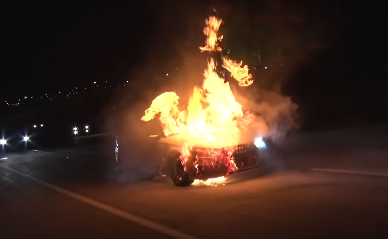 An Audi RS3 in flames on a highway at night.