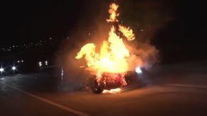 An Audi RS3 in flames on a highway at night.