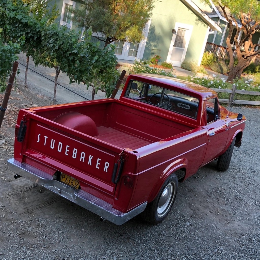 A rear overhead view of the red 1962 Studebaker Champ in front of a country home
