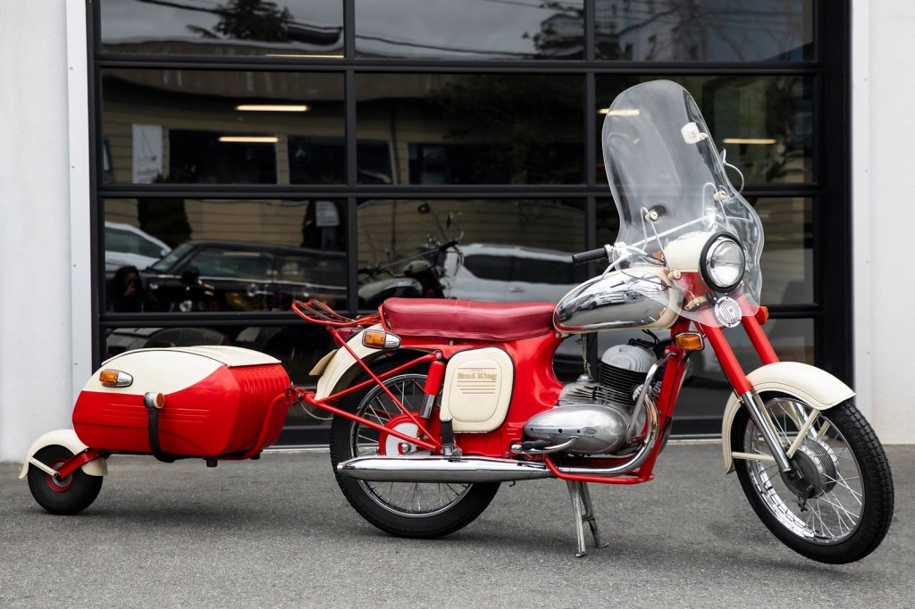 A red-and-white 1966 Jawa 350 with a one-wheel red-and-white trailer