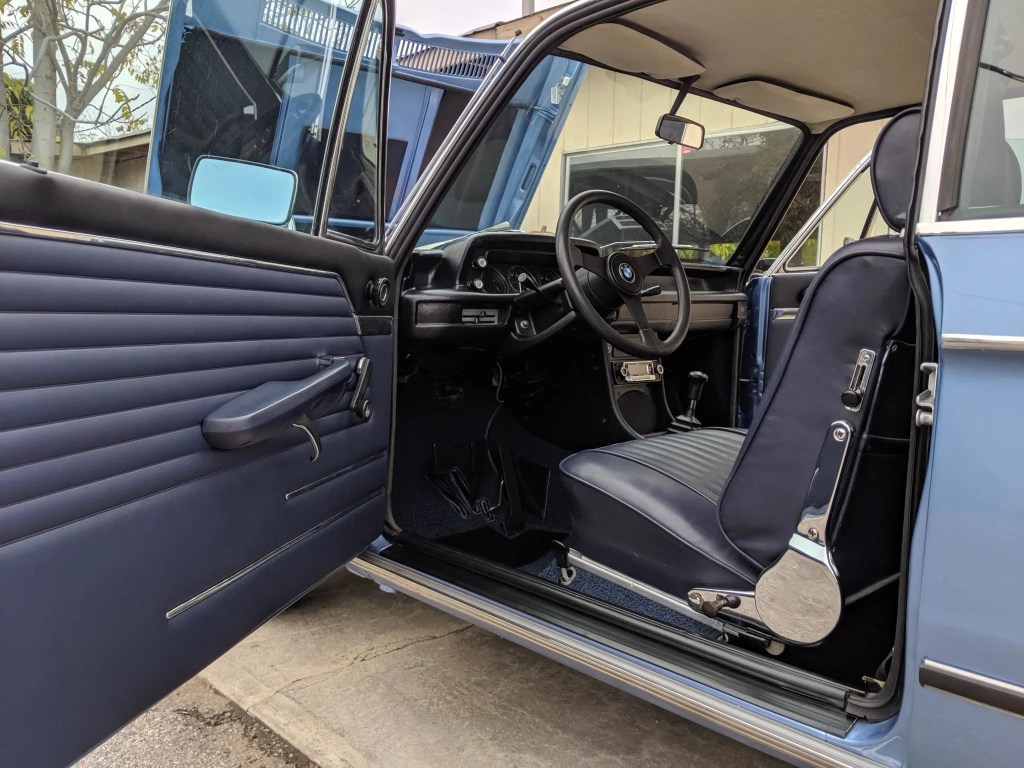 The interior of a blue 1972 BMW 2002tii, as seen through the open driver's door