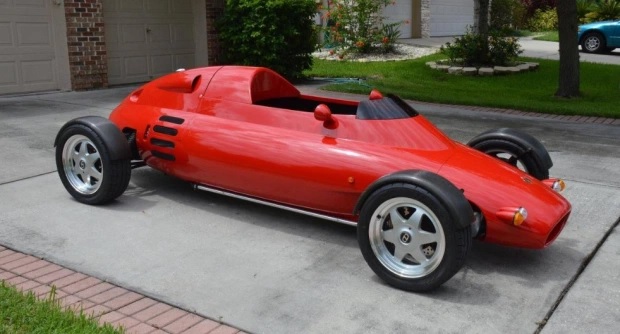 The side view of a red 1992 Light Car Company Rocket parked in a driveway