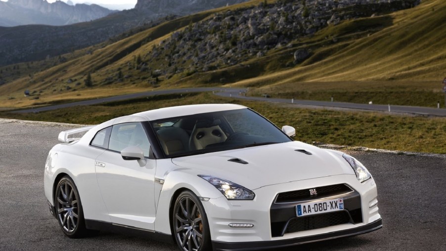 A white 2011 Nissan GT-R in green rolling rocky hills