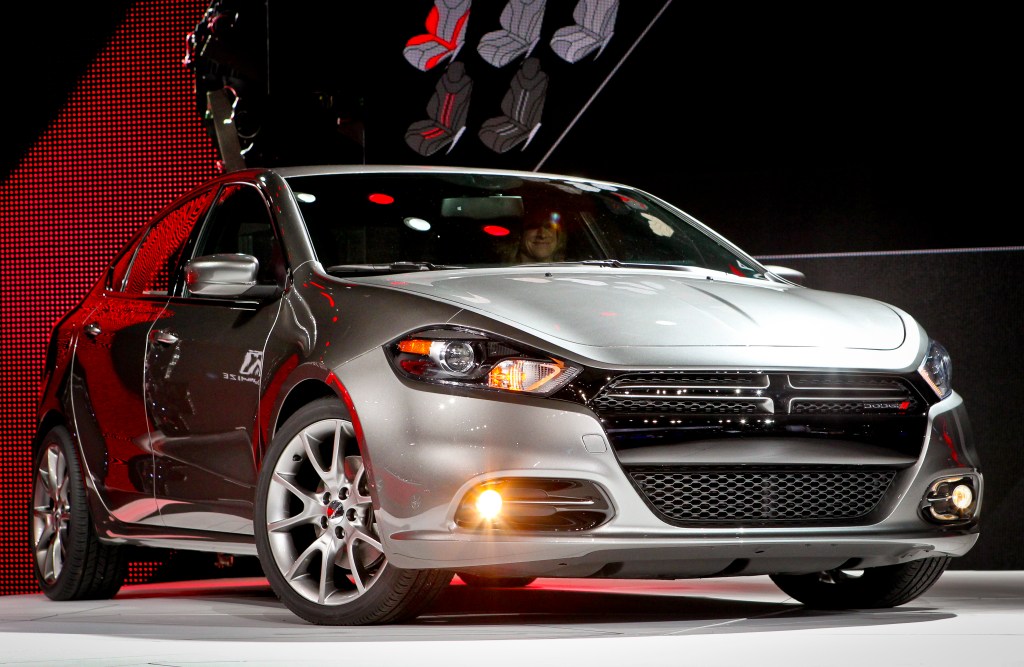 A silver 2013 Dodge Dart sits on display at a car show.