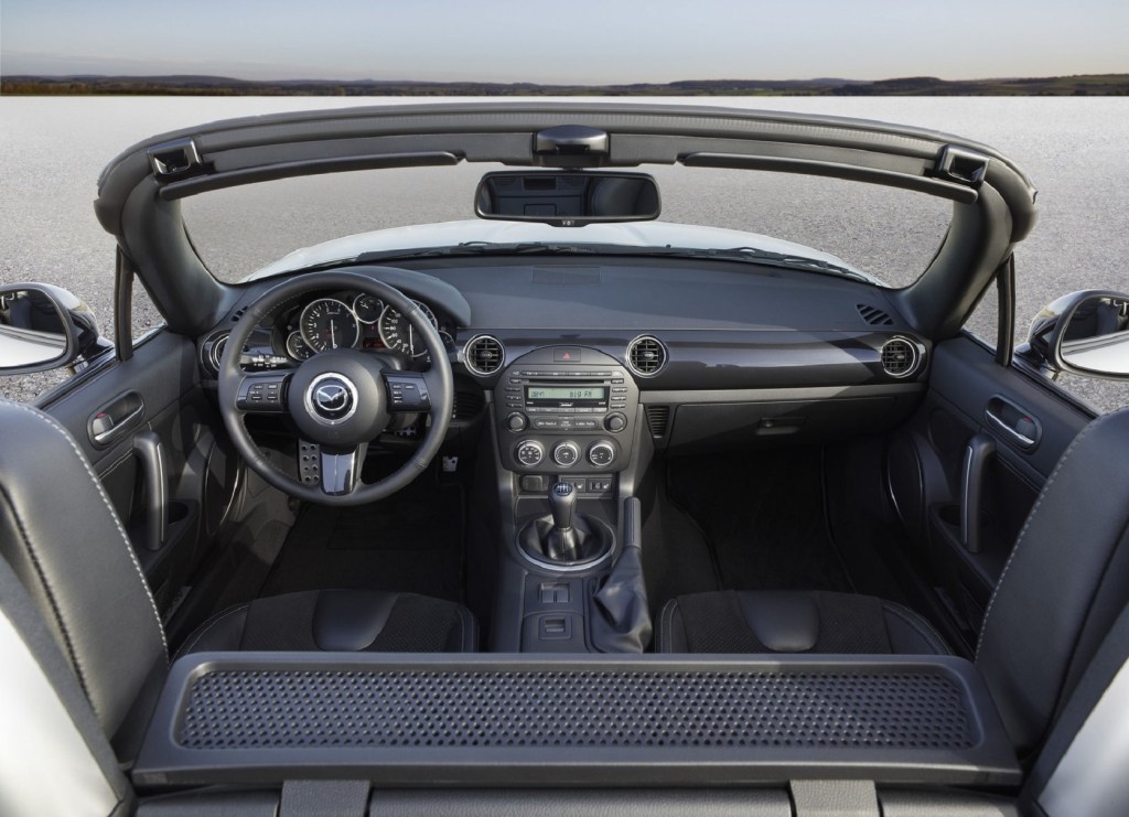 The black interior of a 2013 Mazda MX-5 Miata with its roof down