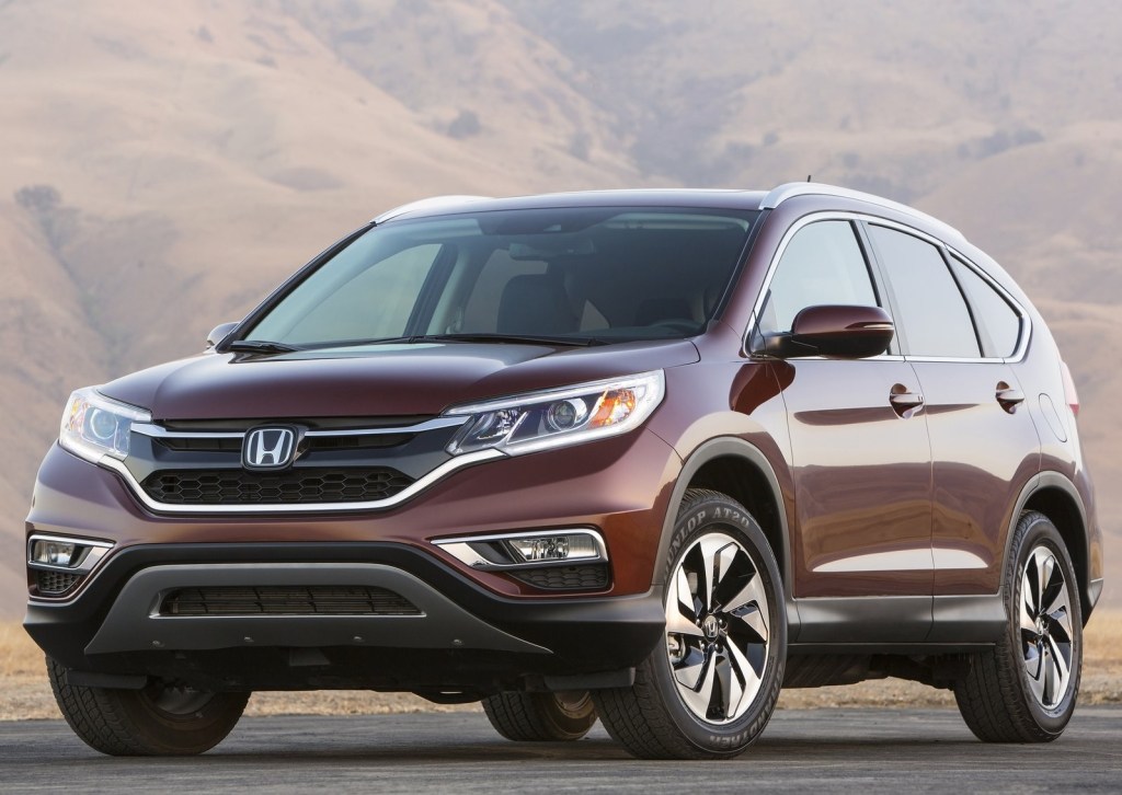 a 2015 honda cr-v in a burgundy color parked with a mountainous backdrop