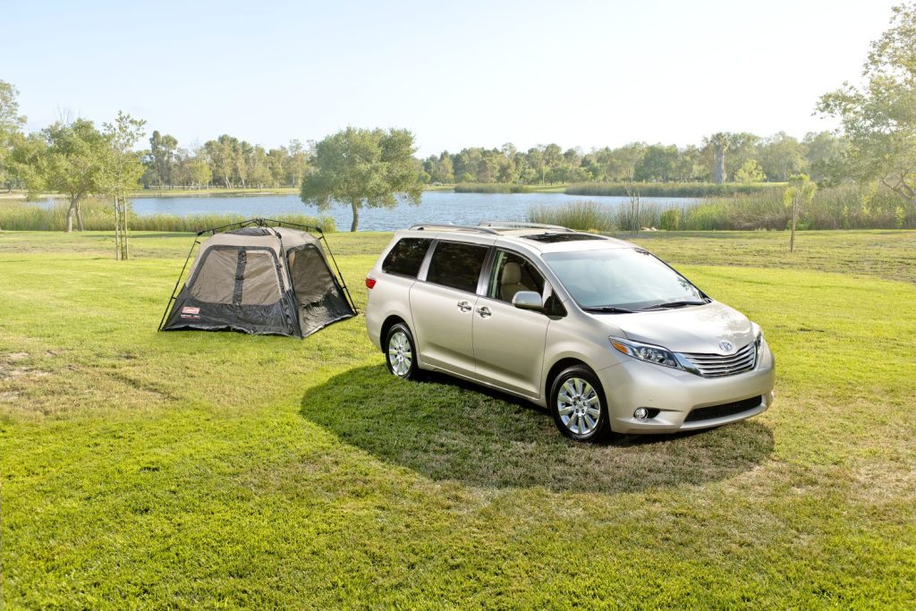 a sliver Toyota Sienna in a natural area, set up for camping