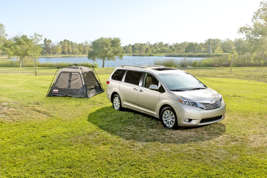 a sliver Toyota Sienna in a natural area, set up for camping
