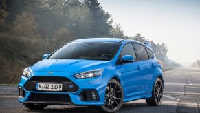 A blue 2016 Ford Focus RS on a tree-lined misty road