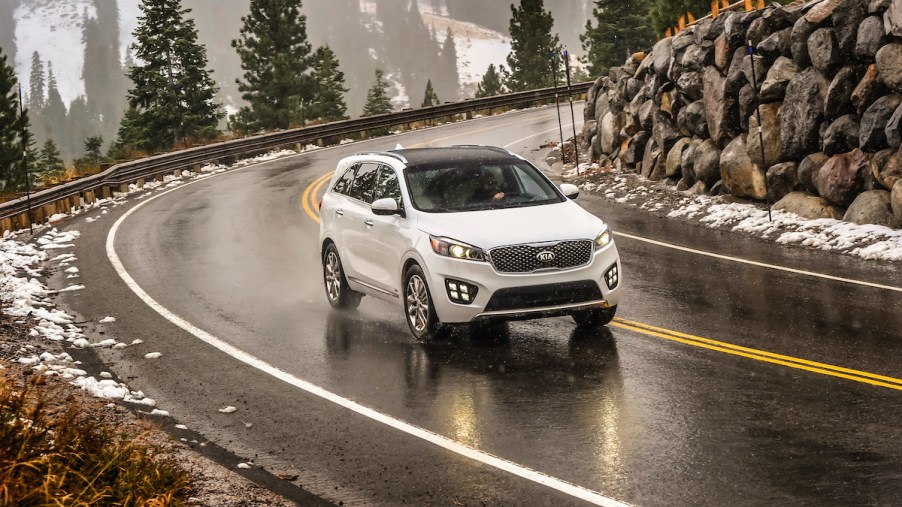 2017 Kia Sorento driving through a snowy and icy mountain road with evergreen trees and rocks in the background