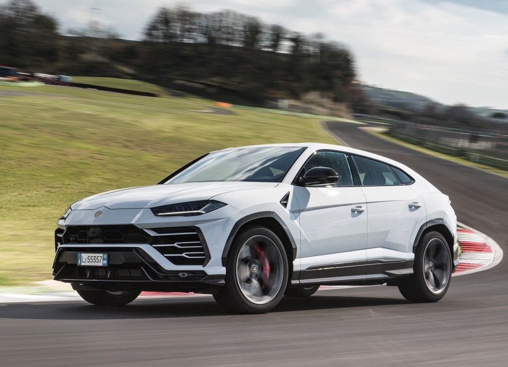 A white 2019 Lamborghini Urus takes a corner on a racetrack
