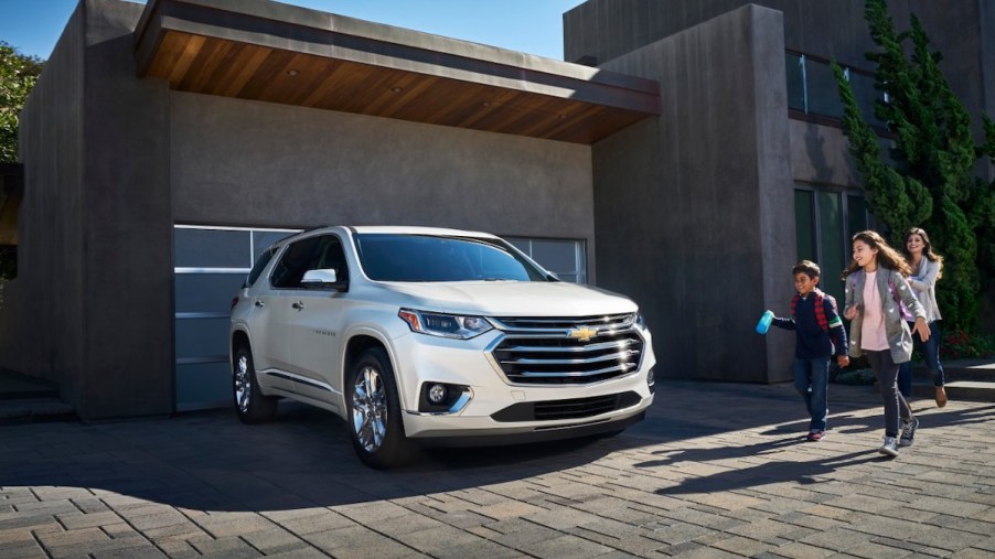 2020 Chevrolet Traverse parked outside a house with a family excited to get into the SUV
