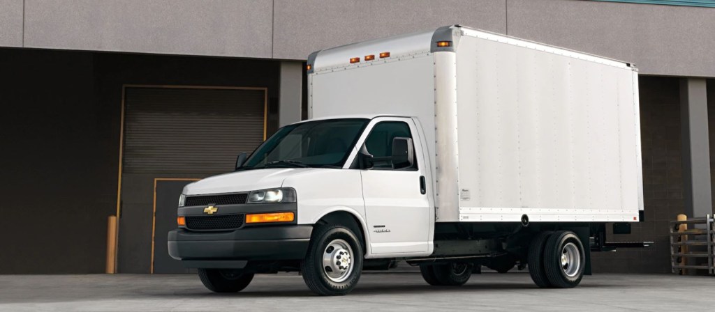 A white commercial box truck sit by a loading dock.