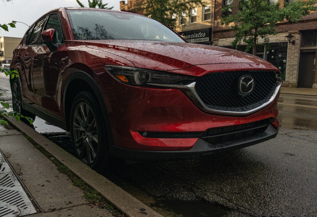 A front-3/4 view of a red 2020 Mazda CX-5 Signature AWD parked on a rainy street