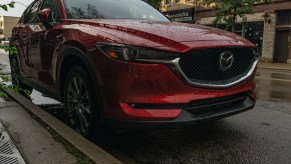 A front-3/4 view of a red 2020 Mazda CX-5 Signature AWD parked on a rainy street