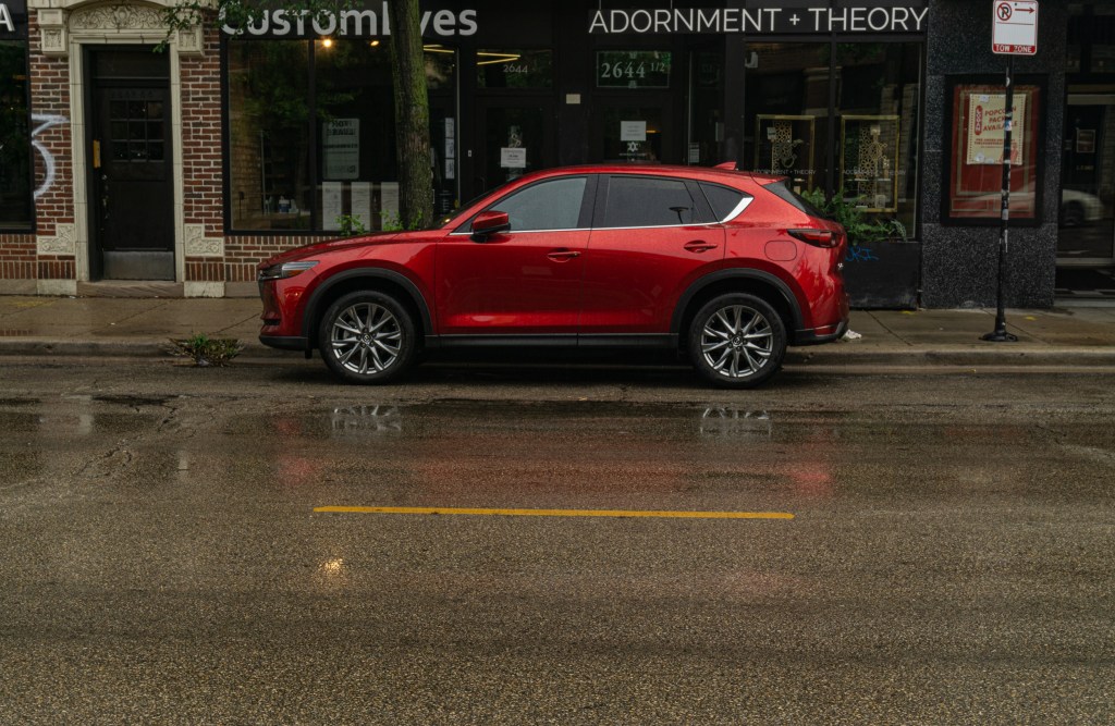 The side view of a red 2020 Mazda CX-5 Signature AWD on a rainy city street