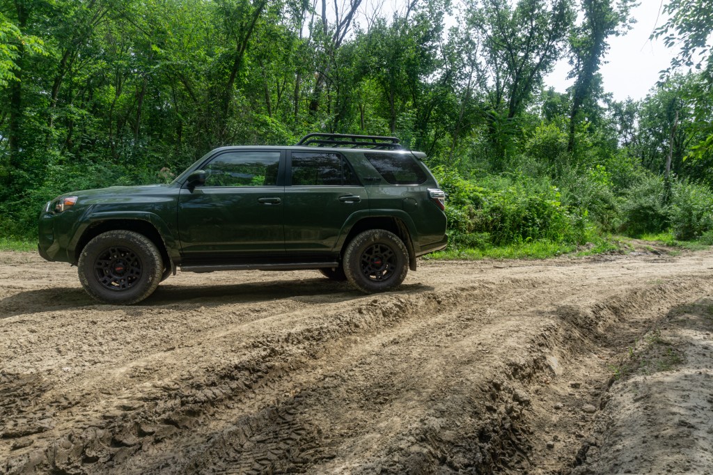 A green 2020 Toyota 4Runner TRD Pro on a forested muddy rutted off-road trail