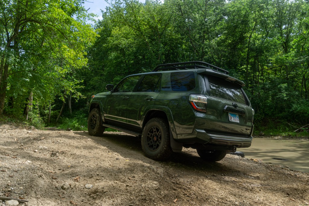 A rear shot of a green 2020 Toyota 4Runner TRD Pro on a forest off-road trail near a creek