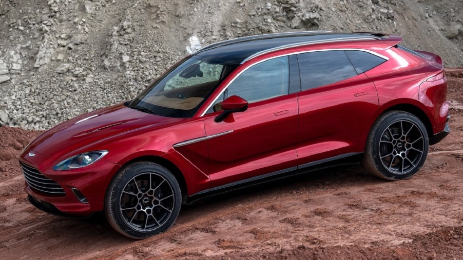 The side view of a red 2021 Aston Martin DBX as it descends a rocky trail