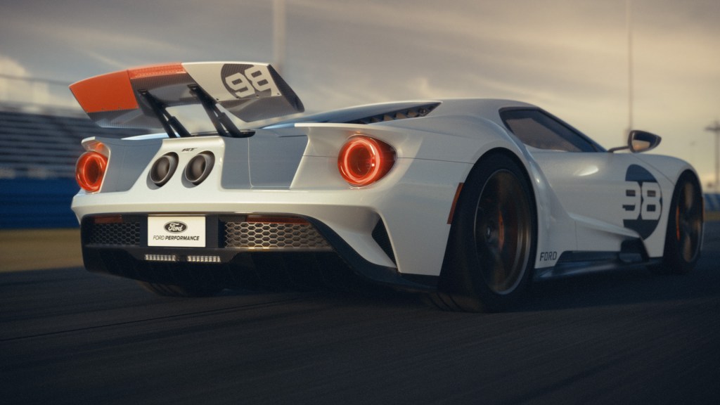 The rear of a white 2021 Ford GT with black and red racing livery attached to it is seen at a race track.
