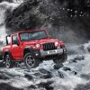 A red 2021 Mahindra Thar with its roof off crosses a roaring river
