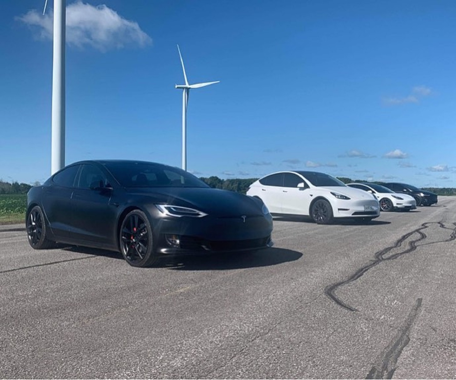 The 2021 Tesla Performance lineup, with a black Model S in front of a white Model Y in front of a white Model 3 in front of a black Model X