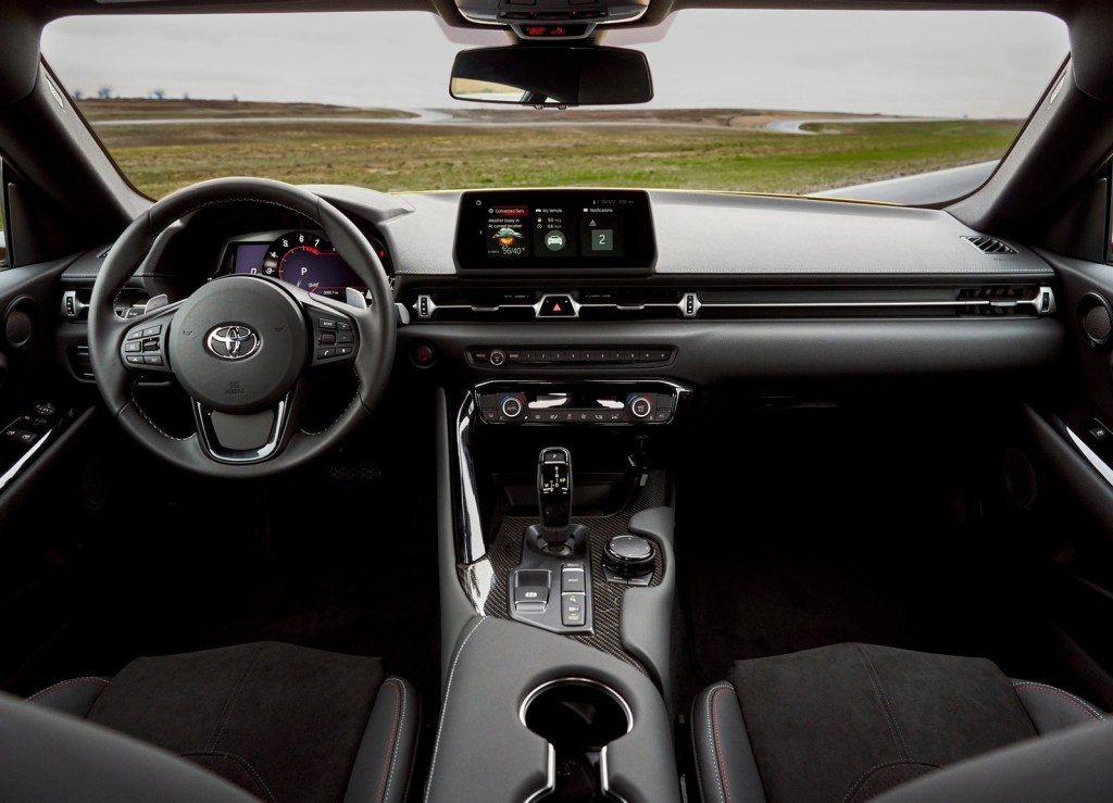 The interior of a 2021 Toyota Supra 2.0, showing the center touchscreen, carbon-fiber trim, and leather-trimmed sport seats