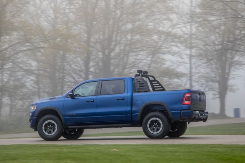 a blue Mopar ram off-road build with aftermarket accessories driving on a scenic road