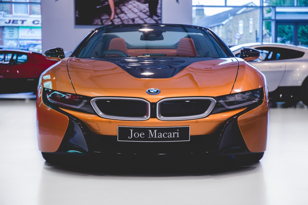 The BMW i8 in the Joe Macari Performance Cars Showroom. The BMW i8 was designed by Benoit Jacob and the production model was unveiled at the 2013 International Motor Show in Germany. It features butterfly doors, head-up display, rear-view cameras and partially false engine noise