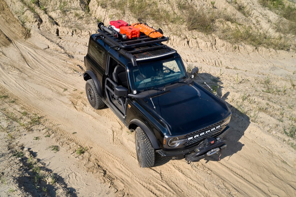 A black, two-door 2021 Ford Bronco with tube doors on a dirt road can be seen from above.