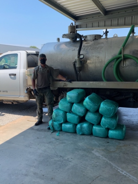 An police officer stands by bundles of drugs that were found in a septic truck tank.