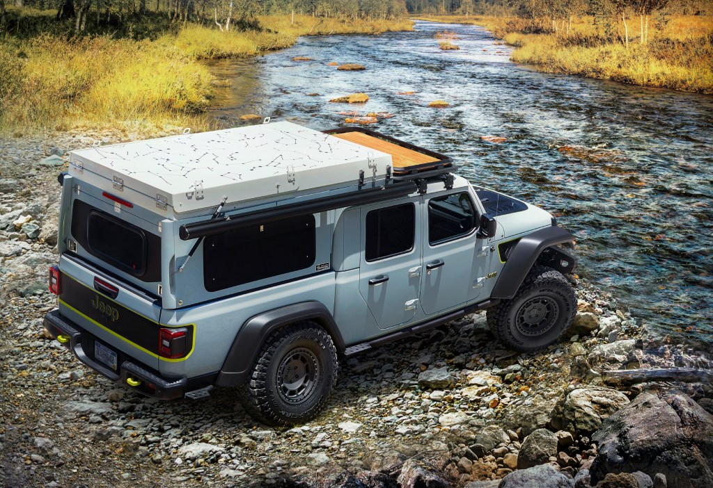 A gray Jeep Gladiator pickup is parked on bank of a creek.