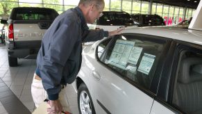 Car Sales: A man inspects a car inside a dealership
