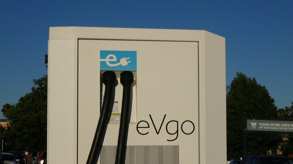 An EVgo station is pictured against a sunny background. 