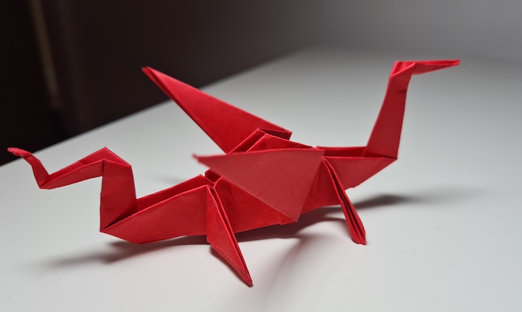 Stunning photo of an intricate red origami dragon on a white surface.