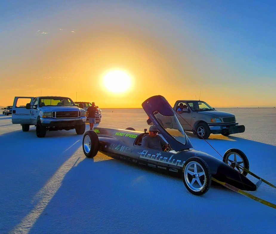 The Electraline Lakester electric vehicle is in the foreground of the Bonneville Salt Flats, with the sunrise in the distance.