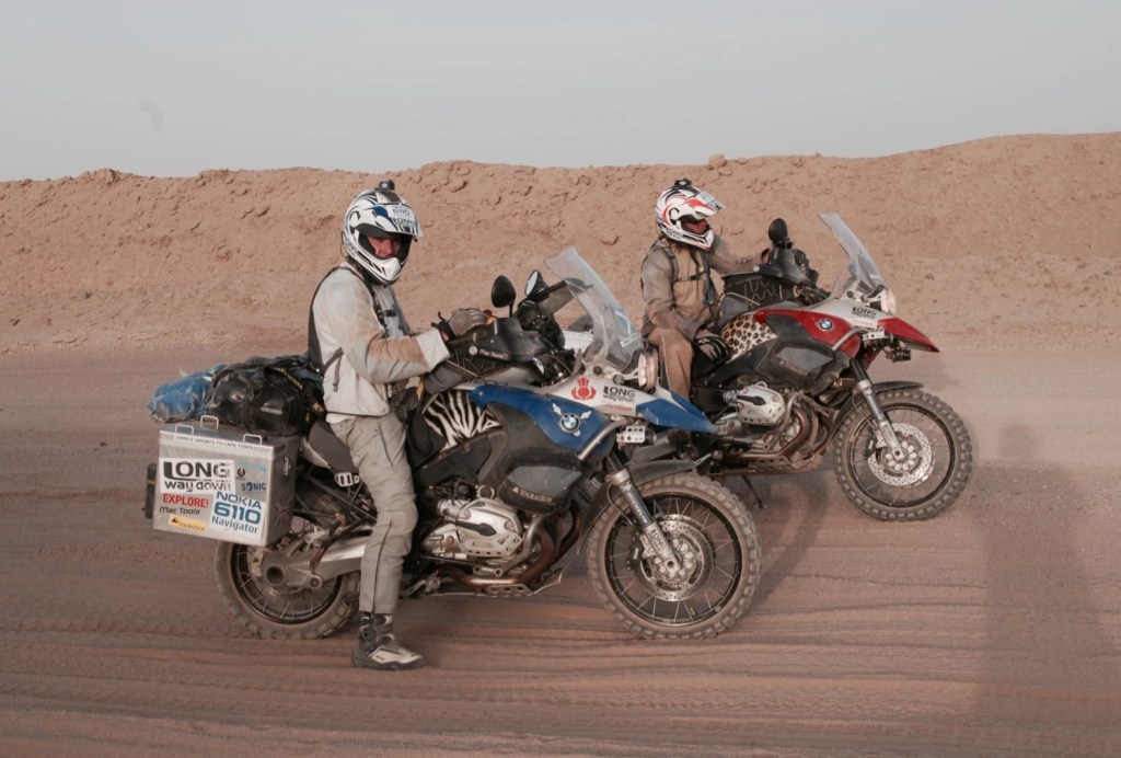 Ewan McGregor and Charley Boorman with their blue and red BMW R1200GS Adventures in the desert