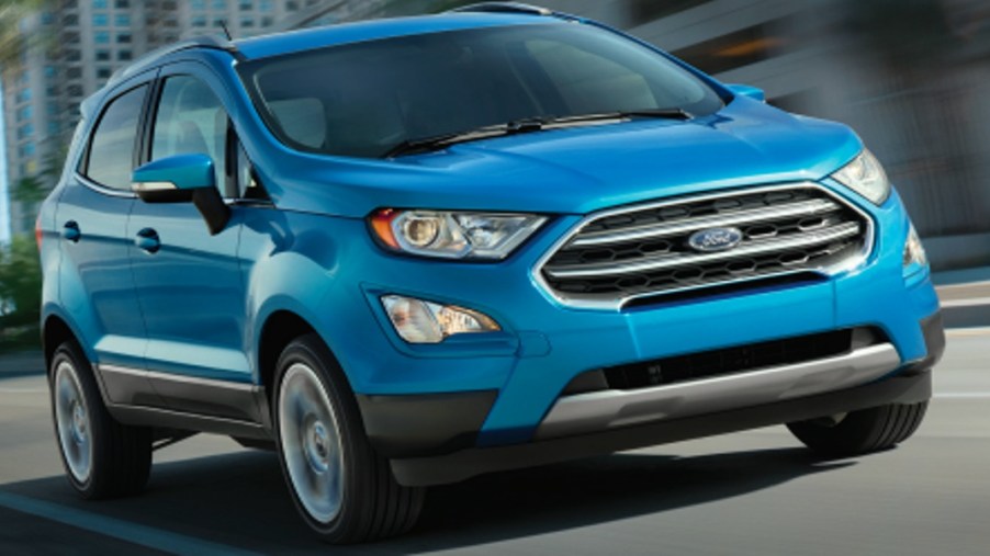 A blue 2018 Ford EcoSport subcompact SUV is driving on the road.
