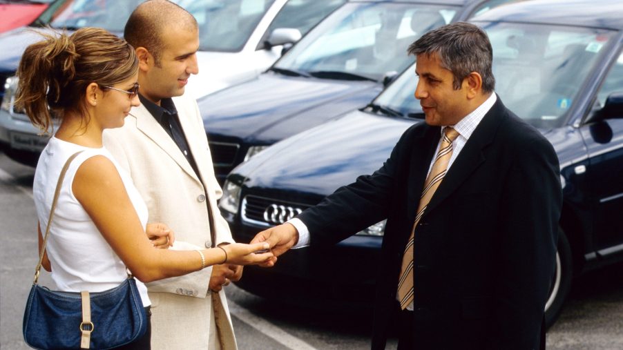 a car dealer shakes hands with clients.